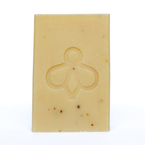 Lavender and Goat’s Milk Soap - A creamy-coloured bar with black speckles, featuring our bee imprint, displayed against a clean white background. Immerse yourself in the soothing blend of lavender and goat’s milk for a gentle and nourishing bathing experience.