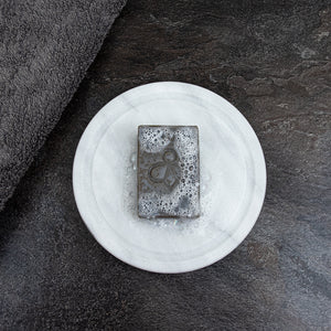 Worker Bee Scrubby Soap on Dish - Featuring a black slate background, our Worker Bee Soap rests on a dish, enveloped in refreshing suds. Experience the powerful cleaning performance of our soap, specially designed for tackling tough grease and grime with ease.